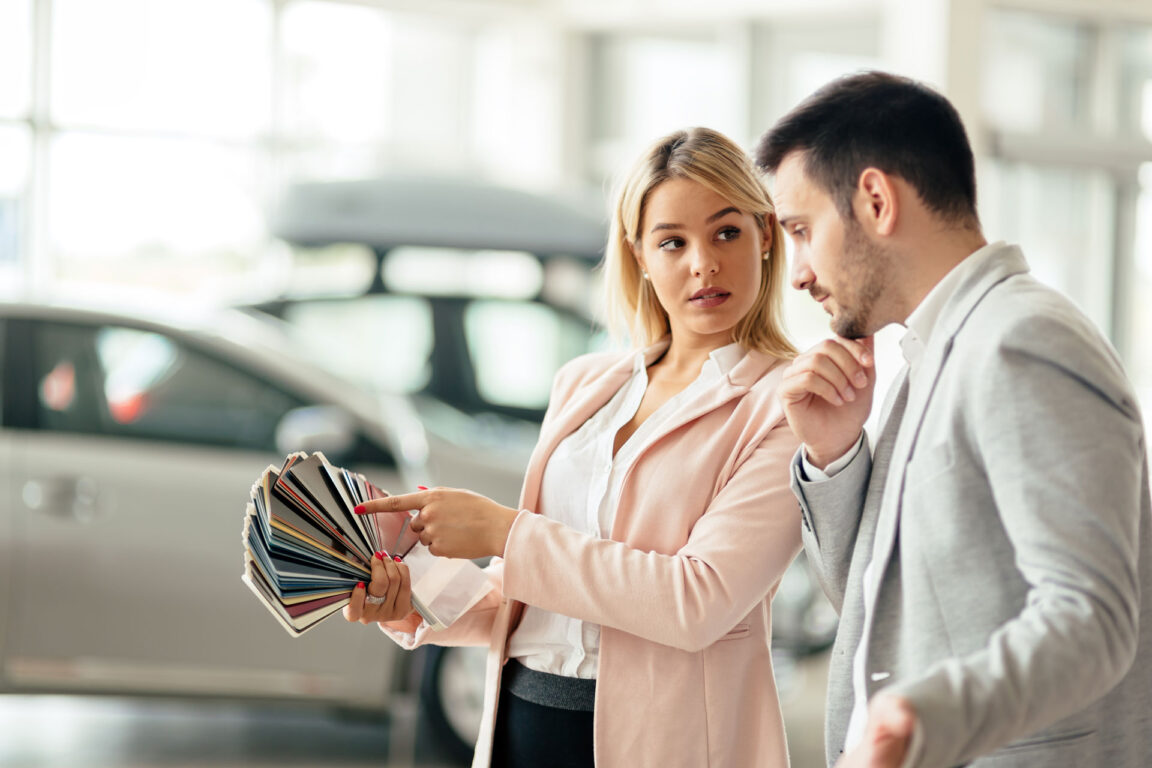 woman picking a car color from swatches with a car salesman