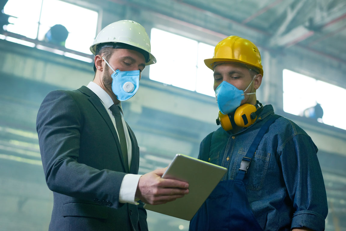two factory workers looking over a tablet