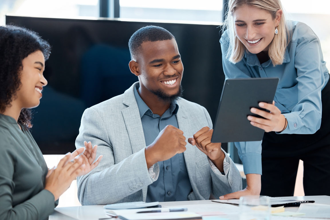 African American businessman smiling and looking at smart tablet with coworkers