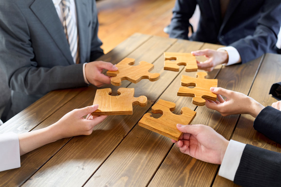 business-person-with-puzzle-pieces business owners holding wooden puzzle pieces